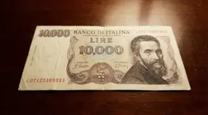 Banconota da 10.000 lire con ritratto e dettagli visibili su sfondo in legno