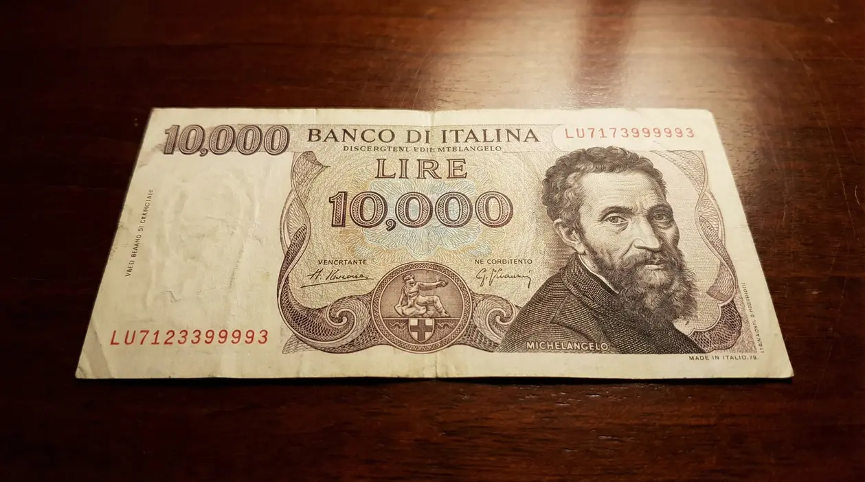 Banconota da 10.000 lire con ritratto e dettagli visibili su sfondo in legno