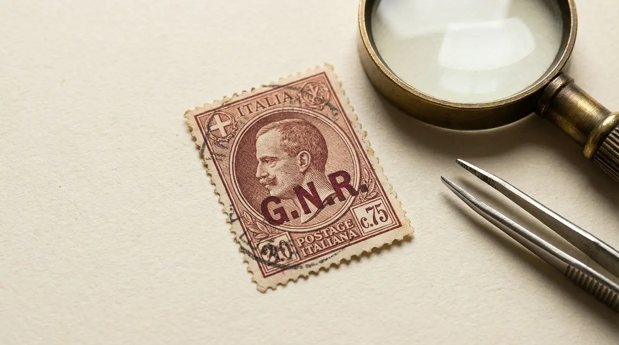 Francobollo GNR del 1944 su sfondo chiaro con lente d’ingrandimento e pinzetta