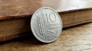 Vecchia moneta italiana da 10 lire con spiga d’orzo appoggiata su un tavolo di legno