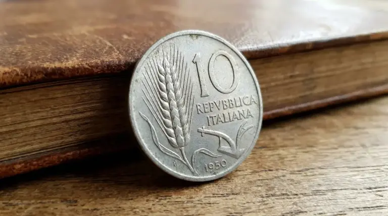 Vecchia moneta italiana da 10 lire con spiga d’orzo appoggiata su un tavolo di legno