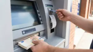 Una persona preleva contanti da uno sportello bancomat inserendo una carta